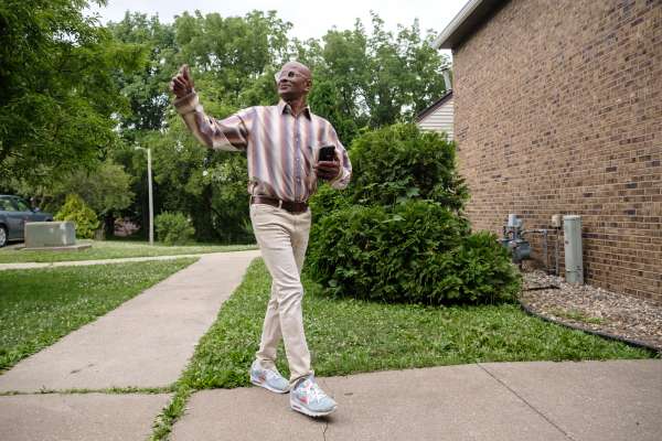 Photo of A man smiling and waving as he walks by.